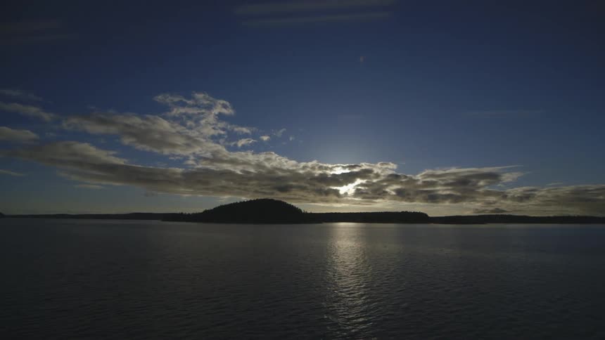 Clouds float over a land mass and the ocean