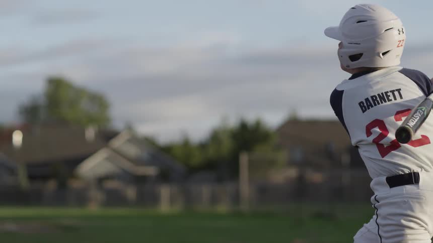 A youth hits a baseball with a bat
