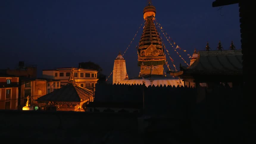 A row of homes and a pillar are lit up at night