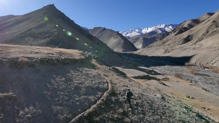 Person hiking along a dry mountain range on sunny day