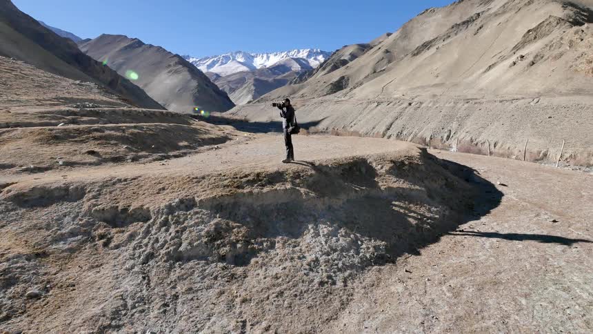 A man takes pictures on a rocky hill
