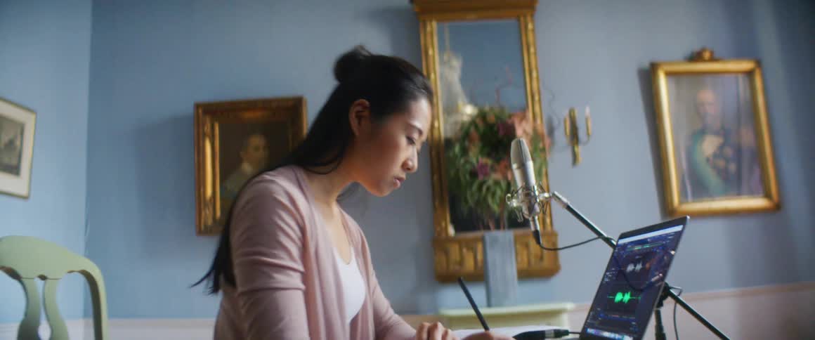 A woman is sitting at a desk next to a laptop