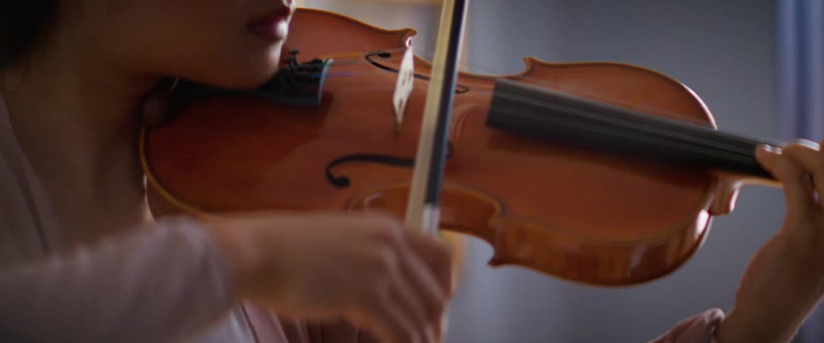 A woman is playing the violin indoors