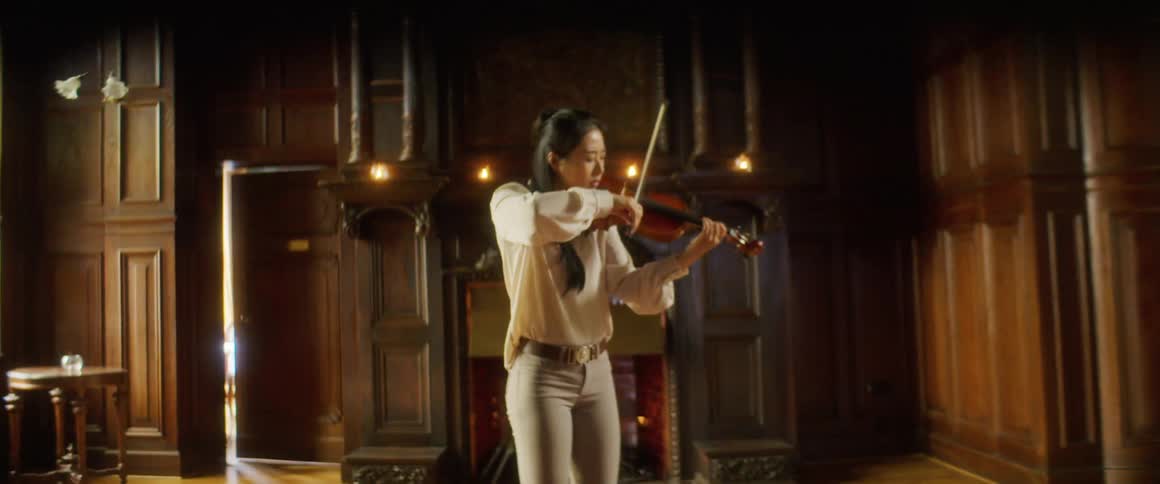 A woman is playing the violin in the large room