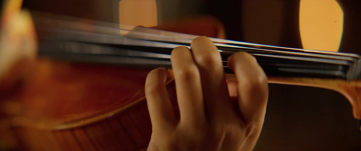 A violinist runs her fingers along the strings of the instrument