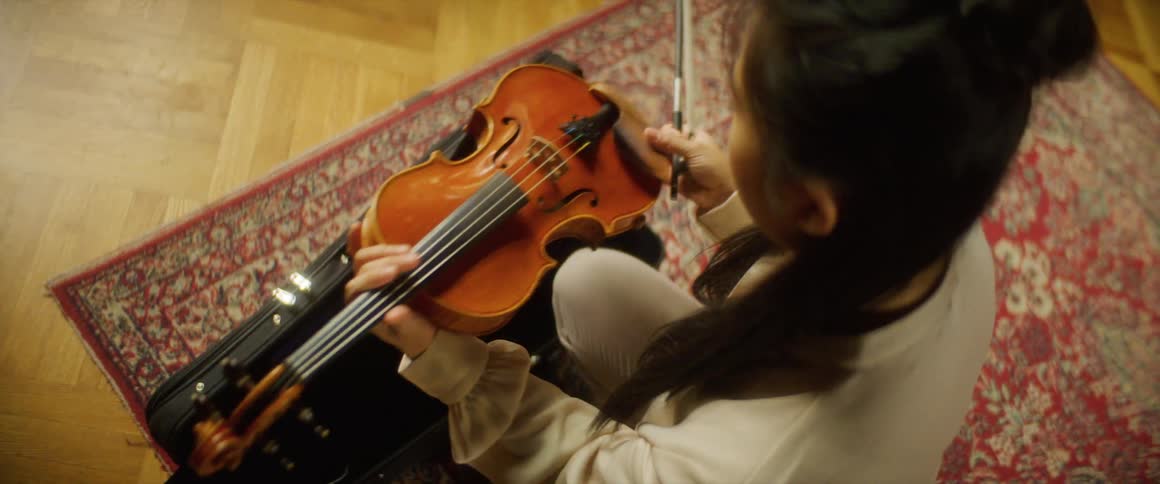 Young girl lifts and positions her violin on her shoulder