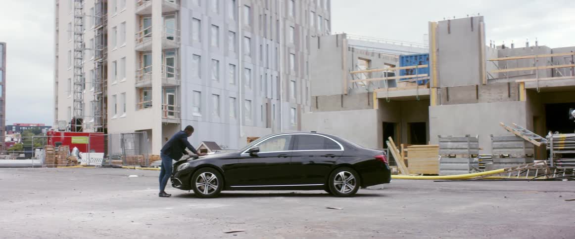 A man is standing by his parked car in a city