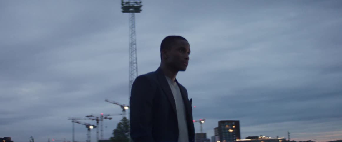 A man is standing outdoors in a city at dusk