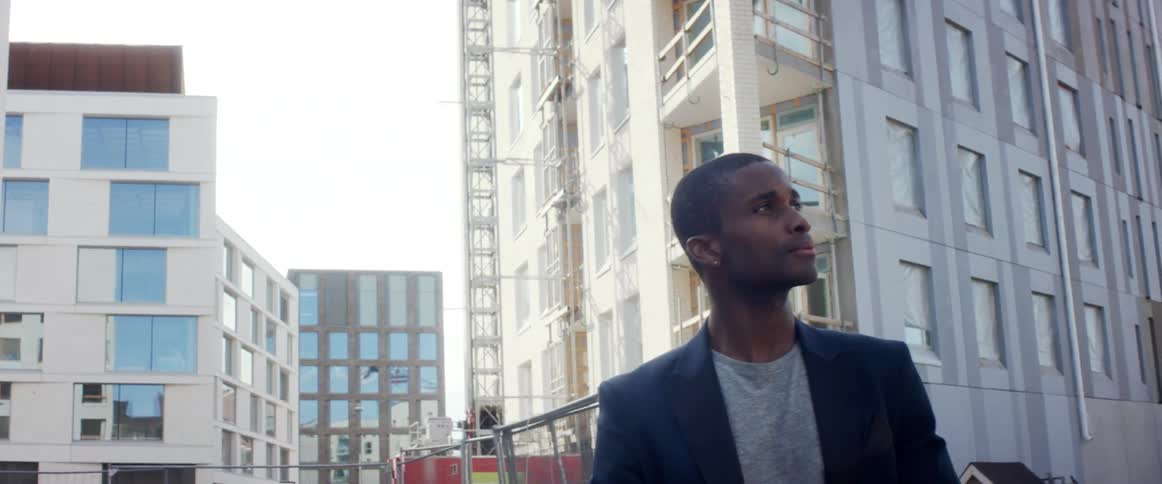A man looks around in front of a construction site in a downtown area