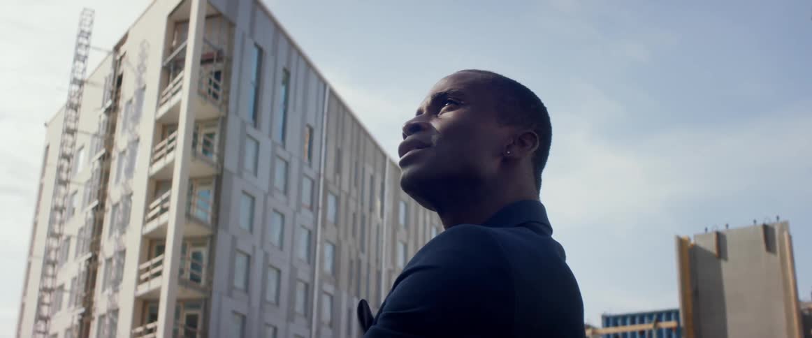 A man stands outside and looks up at apartment buildings under construction