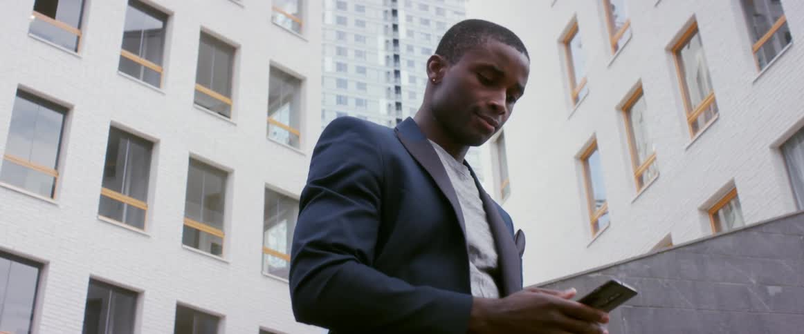 A man in front of a apartment buildings talks on his phone