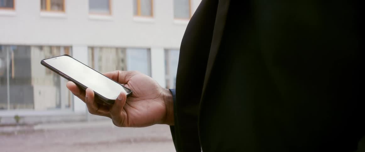 A person standing outside a building looks at his cell phone