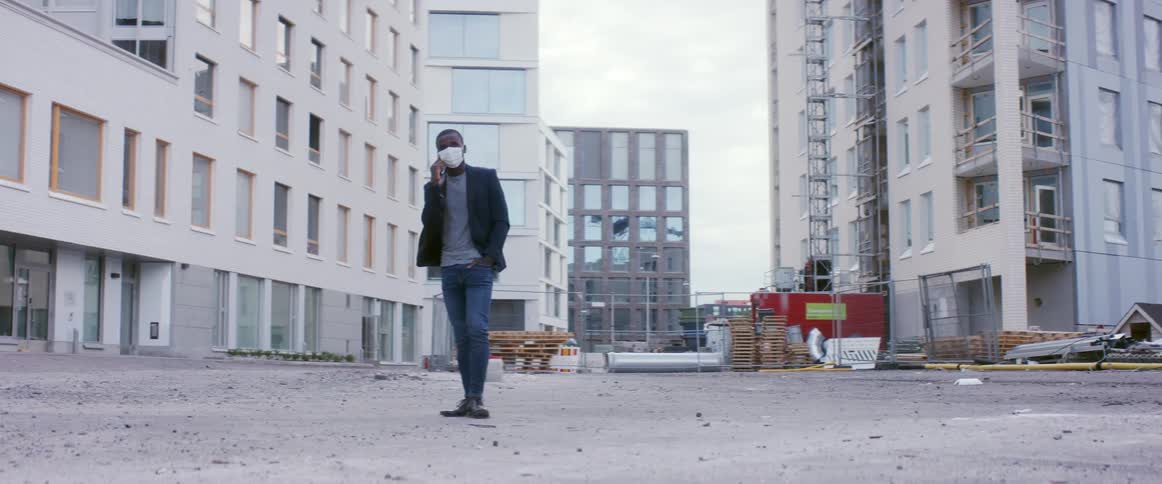 A man talks on the phone as he walks around a construction site where apartment buildings are going up