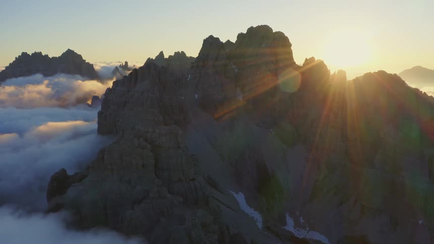 A mountain range with a sunset the sky and clouds in the background