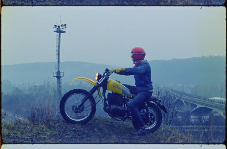 A man is sitting on his motorcycle on the hill