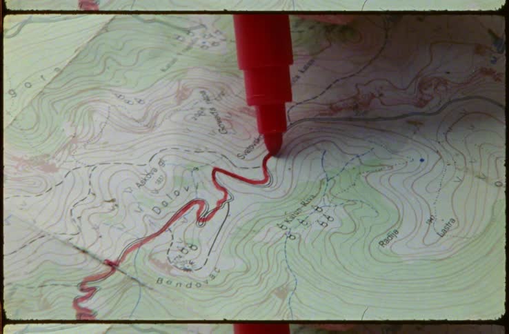 Person traces route on map in red ink
