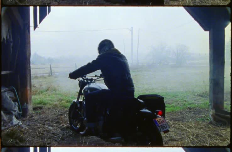A man puts on his helmet before getting ready to take off on his motorcycle