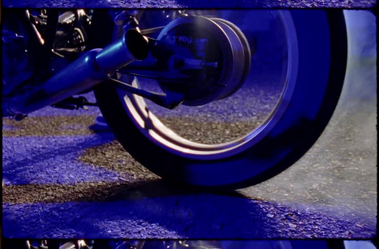 A motorcycle tire spinning on gravel with smoke coming out of it