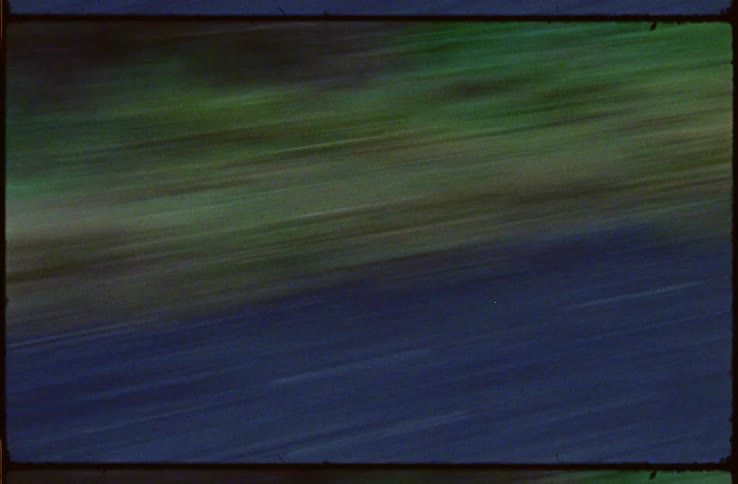 Asphalt road and slightly brown vegetation passes in a blur