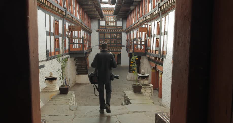 Man with camera equipment walking through a temple