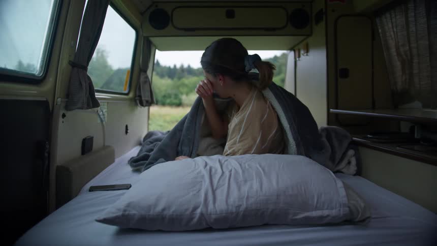 A woman wakes up on the bed in her van