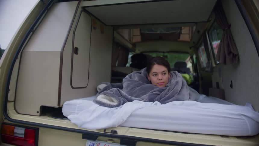 A woman is sleeping on a bed in her vehicle
