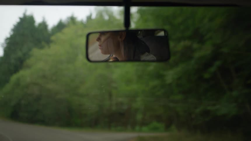 A woman is driving a car during the day in spring