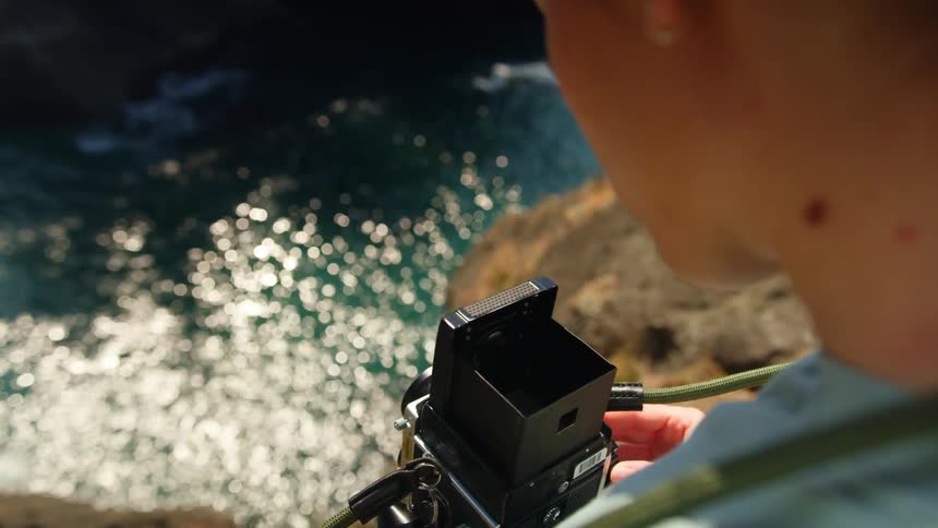 Boy takes video of the sea on rock face