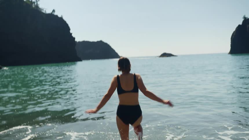 A woman runs from the beach into the ocean water