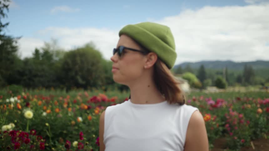 A woman is walking through a meadow of flowers