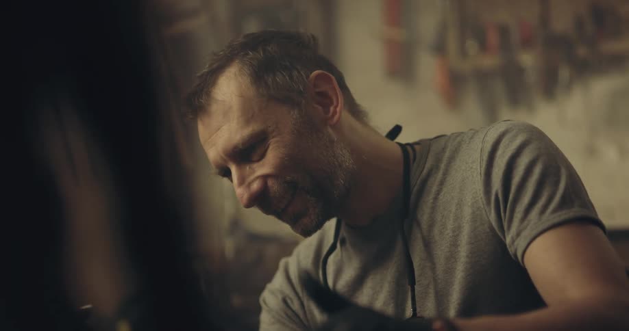 Man holds a chair while painting it with paint and a paintbrush
