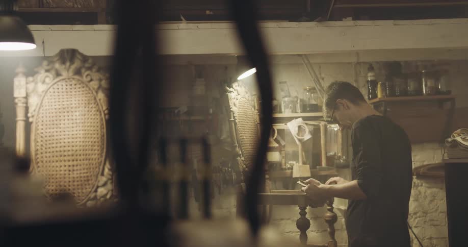 A wood worker sands a chair