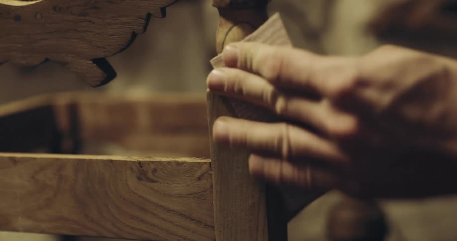 A man standing a chair he is making