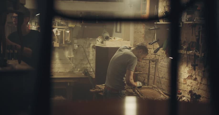 Two men in a workshop working on wooden chairs