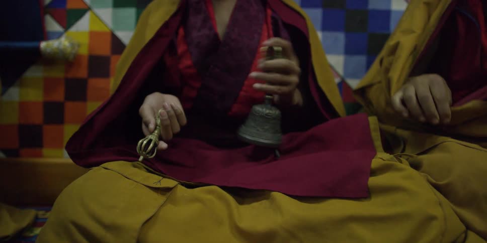 Buddhists monks sit ringing bells