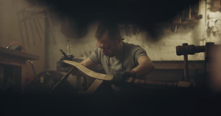 Man wears gloves while working with wooden chair in his workshop