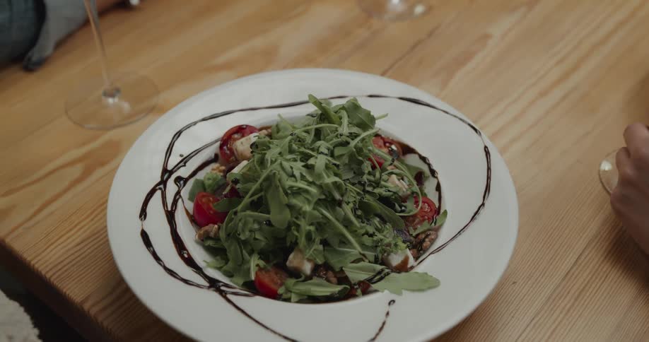A plate of salad being placed in front of a customer in a restaurant