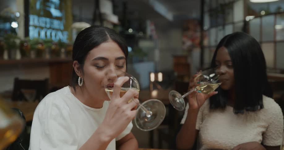 A group of friends in a restaurant clink their glasses together as they toast