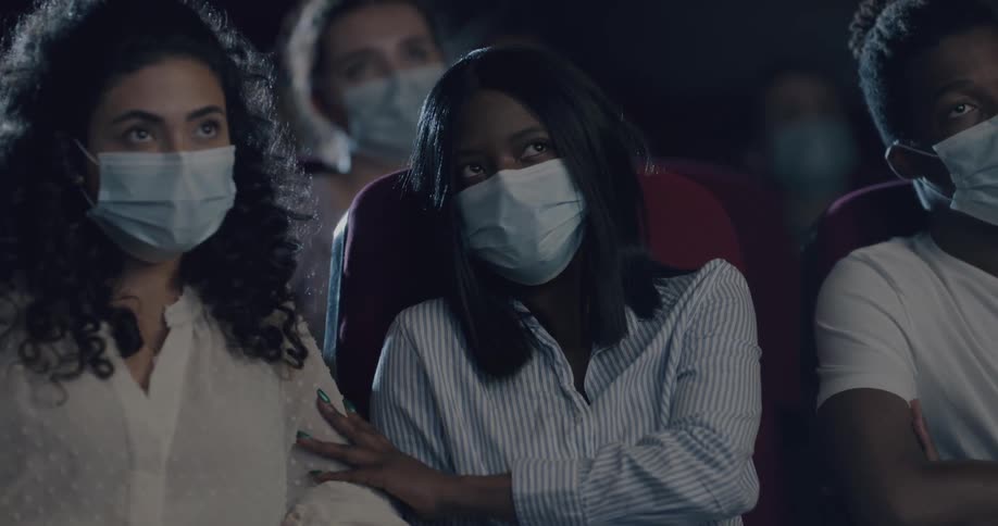 People with masks on a sitting in a movie theater