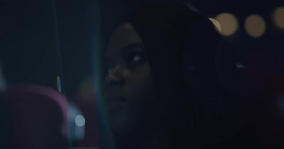 Woman sits in dark movie theater watching movie