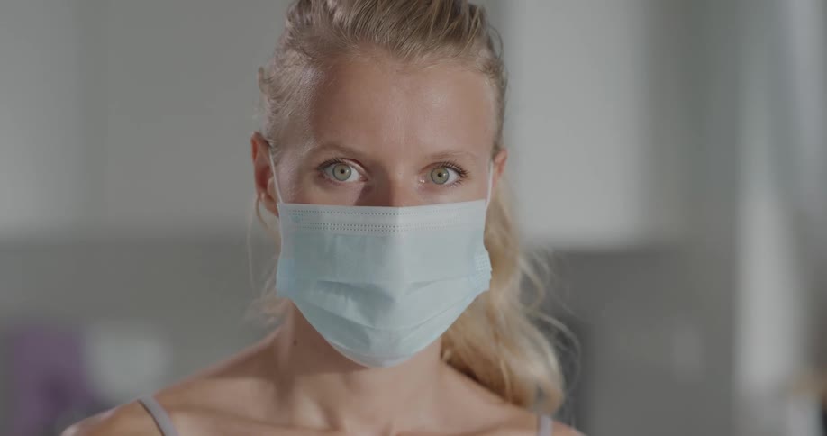 A young woman wearing a mask looks up