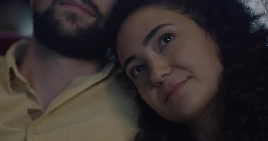 Couple cuddles and watches a movie in the movie theater
