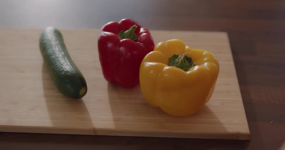 Woman places a variety of vegetables on chopping board on wooden surface