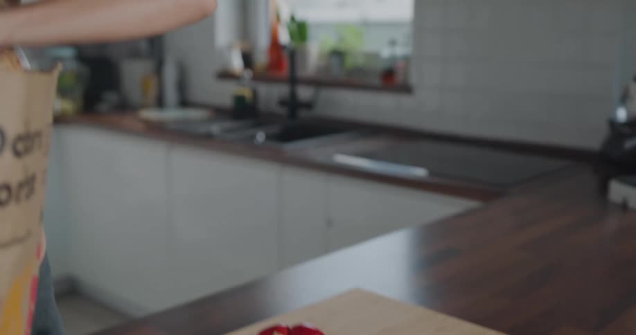 Blonde woman with a ponytail puts vegetables on a cutting board in the living room