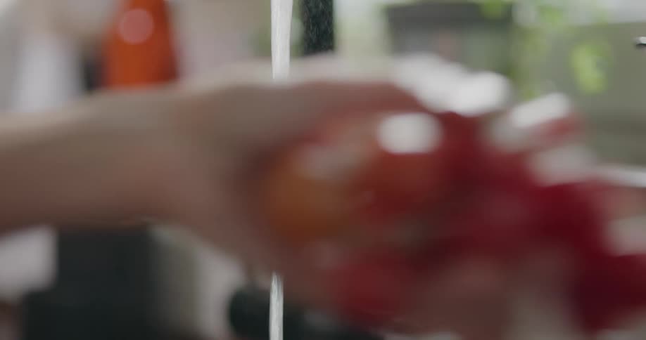 A woman washes vegetables in her kitchen sink
