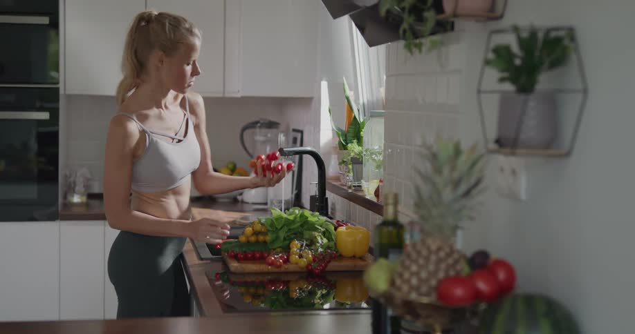 A woman is washing vegetables in the kitchen