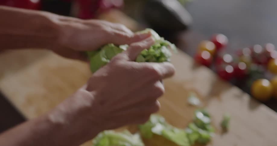 A woman at home rips lettuce and puts it in a salad