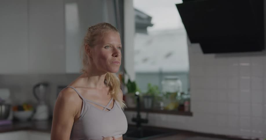 A woman takes a single forkful of salad from a large bowl before walking away