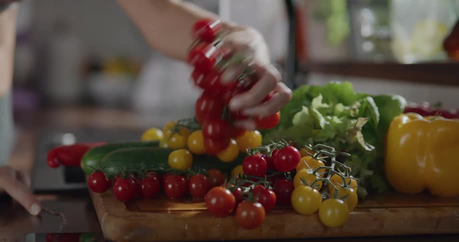 Woman washes yellow and red tomatoes in the kitchen