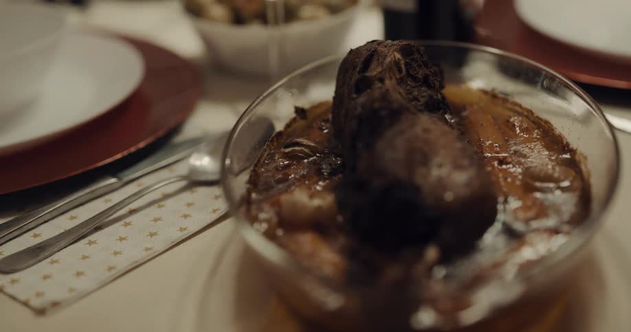 A bowl of cooked juicy meat sitting on a dinner table